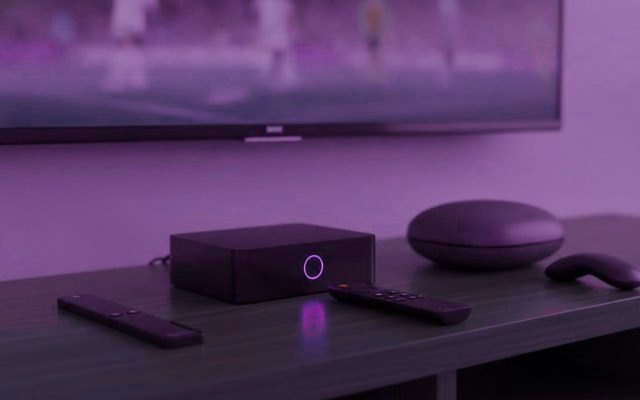 A streaming stick, a set-top box and a round streaming box with their remotes on a TV console