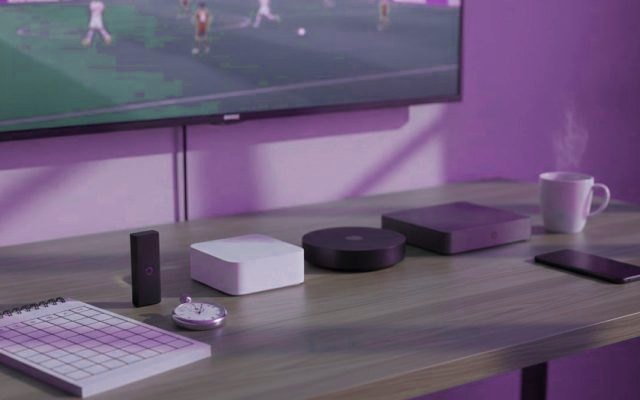 Five streaming devices, a notebook scoring grid and a stopwatch in front of a TV showing a football match