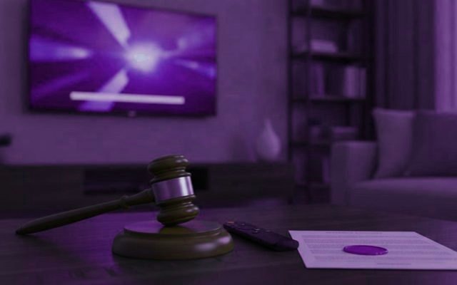 A judge gavel, a streaming remote and a sealed document on a coffee table in front of a TV
